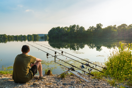 Fishing adventures, carp fishing. Angler is fishing with carpfishing technique in freshwater, in a beautiful summer dayの写真素材