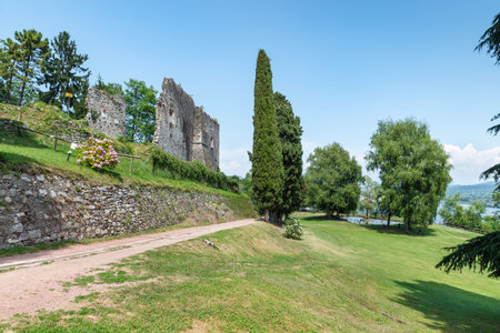 Lake Maggiore, Arona, Italy. Tourist town on Lake Maggiore, Piedmont shore. Public park and the ruins of the medieval rocca (fortress) Borromea of Arona above the city on a beautiful summer dayのeditorial素材