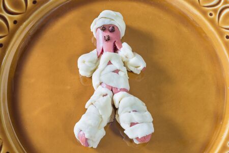 Halloween food. Sausage mummy in dough ready to be cooked. Halloween party appetizer and decorationの写真素材
