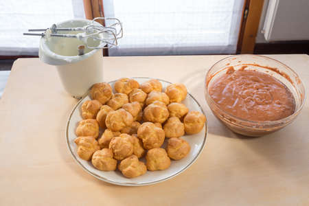 Ingredients for the preparation of profiteroles filled with whipped cream and covered with...