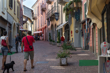 Luino, Italy. Picturesque cobbled alley with traditional restaurants, shops and old houses, street Cavallotti. Scenic Italian village on lake Maggioreのeditorial素材