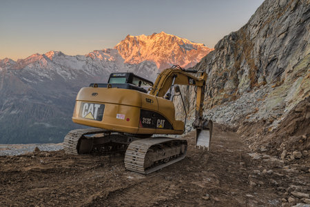 Work at high altitudes in the mountains. Caterpillar excavator building a dirt road. Caterpillar is the world's largest manufacturer of construction equipmentのeditorial素材