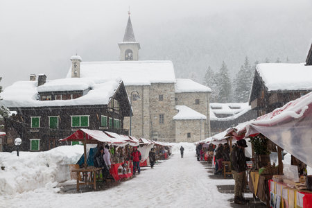 Cold wave and snow in Europe in an alpine mountain village. People are looking for Christmas gifts among the stalls under heavy snow, Macugnaga, north Italyのeditorial素材