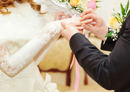 Groom putting a wedding ring on bride's fingerの写真素材