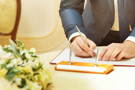 Groom signing marriage license or wedding contractの写真素材