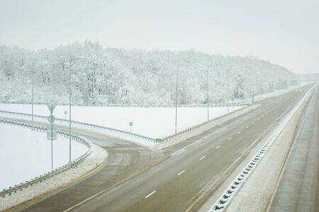 Cold winter landscape of a road through forest trees and heavy snow