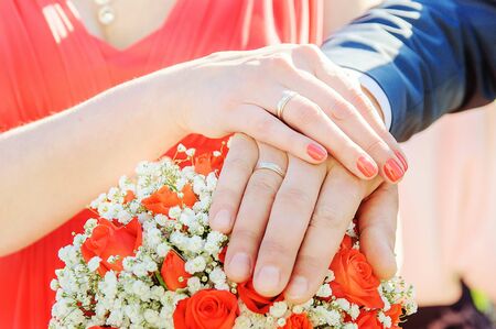 Groom and bride hands and rings on wedding bouquetの写真素材