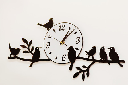 white and black wall clock with birds