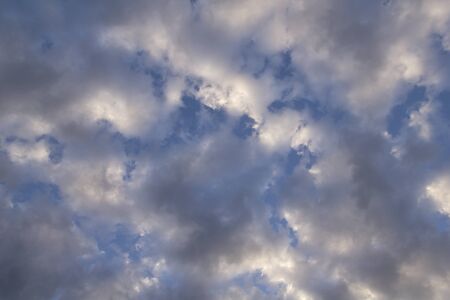 sun and cumulus white clouds against a beautiful blue sky, bizarre patternsの写真素材