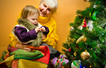 Portrait of happy grandmother hugging her granddaughter over Christmas presents and decorated New Year tree, merry Christmas concept, happy family, lifestyle indoor,の写真素材