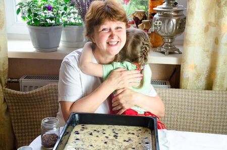 Portrait of faces, hands happy granny hug granddaughter. toddler girl play with grandmother on kitchen. child baby hold grandma and laugh . Cozy family Look at each otherの写真素材