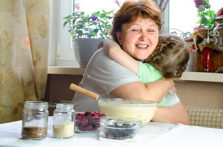 Portrait of faces, hands happy granny hug granddaughter. toddler girl play with grandmother on kitchen. child baby hold grandma and laugh . Cozy family Look at each otherの写真素材