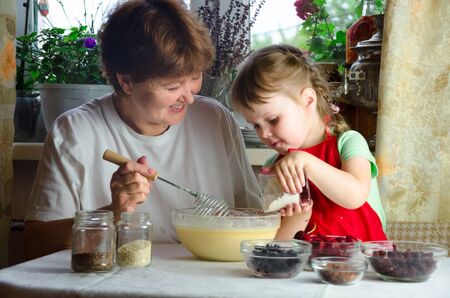 Portrait of faces, hands happy granny, granddaughter. toddler girl play with baking, dough, flour on kitchen. child baby try study cooking cookies, cake. Cozy family Look at each otherの写真素材