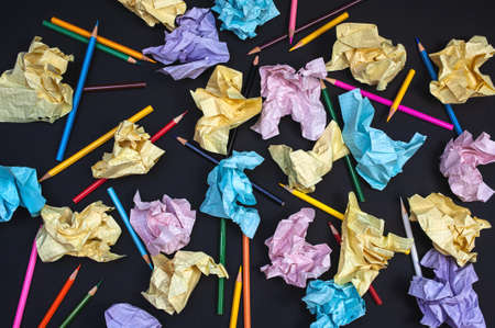 composition of crumpled multi-colored paper and pencils on a dark backgroundの写真素材