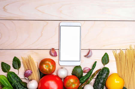 Phone mockup on a background of a wooden board and vegetables.の写真素材