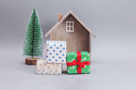 Wooden small house with gifts and Christmas tree against gray background. New Year's composition. Christmas presents.の写真素材