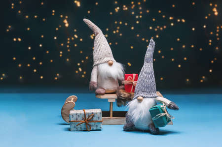 Nisser in Norway and Denmark, Tomtar in Sweden or Tonttu in Finnish, Scandinavian folk elves, northern Christmas motif. Tomte standing against the starry sky with gifts and sledges.の写真素材