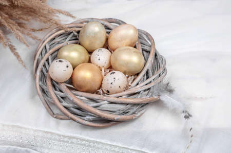 composition of eggs in a nest and feathers on a light background.