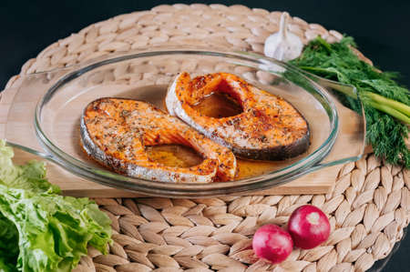 Cooked trout steak on a plate with herbs and vegetables