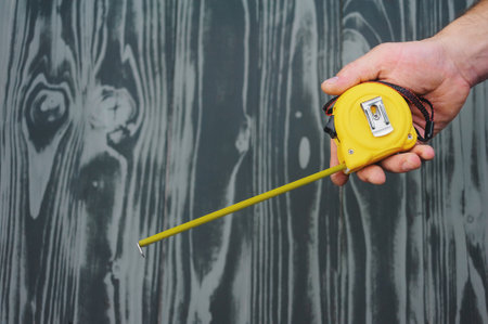 construction tape in hand on gray wooden texture background.の写真素材