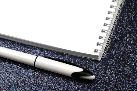 Empty spiral notebook with pen on black.の写真素材