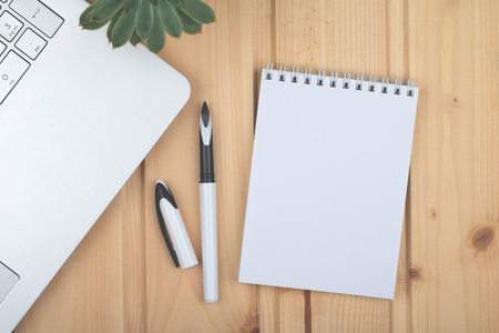 Clean notepad, laptop, pen, on wooden surface.の写真素材