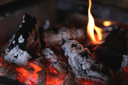Charcoal barbecue with fire burning in rustic fireplace, preparation for outdoor party, roast meat...