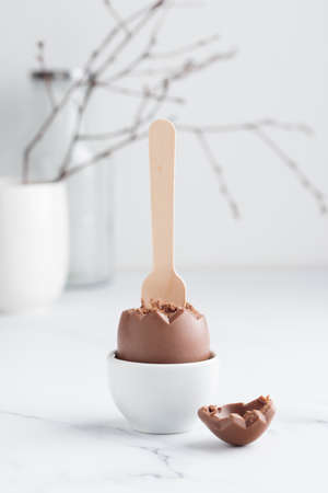 Chocolate easter egg in a white eggholder on a white table