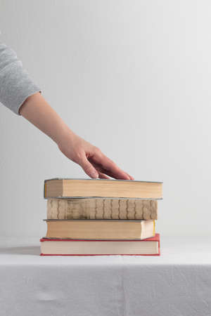 Stack of old rustic vintage books with the hand on white tableの写真素材