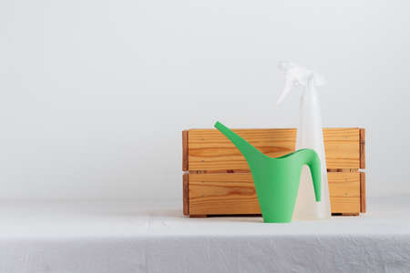 Watering can and spray gun with the wooden box on a tableの写真素材