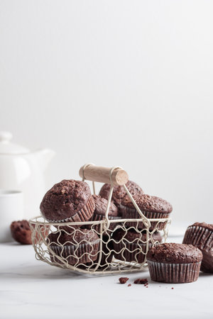 Chocolate muffins in a white basket on a white tableの写真素材