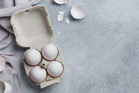 White eggs in a small paper container box top view on a neutral background