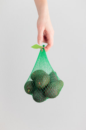 Hand holding an avocado bag on a white backgroundの写真素材