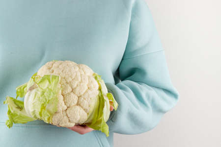 Woman holding a cauliflower head on a white backgroundの写真素材