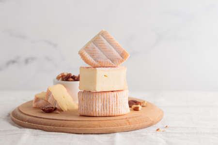 Sliced soft cheese with mold on a wooden board on a white background