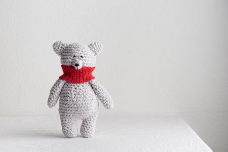 Crochet knitting cute teddy bear with a red scarfの写真素材