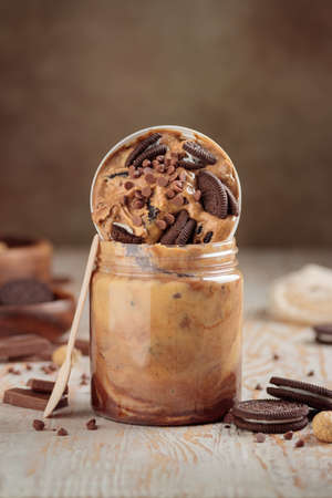 Jar with peanut butter and sweet ingredients on white wooden background closeup