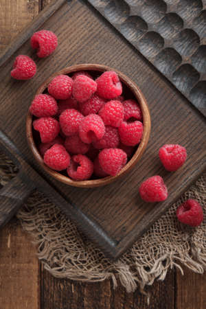raspberry berries in a wooden board on a tableの写真素材