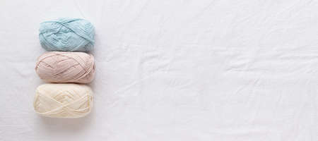 needlework. Balls of cotton yarn pastel colors on a white table, copy space