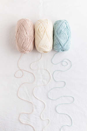 needlework. Balls of cotton yarn pastel colors on a white table, copy space