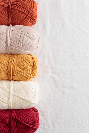 Needlework. Balls of cotton yarn warm colors on a white table, copy spaceの写真素材