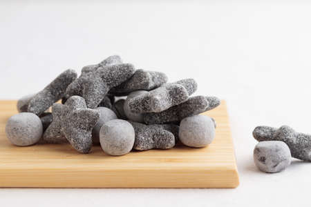 Salty liquorice salmiakki on a wooden cutting board with copy space