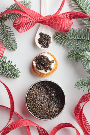 Black caviar appetizers mini pancakes on a christmas decorated white background top view Verticalの写真素材