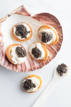 Black caviar and appetizers mini pancakes with a pearl spoon top view Vertical on a white background with a copy spaceの写真素材