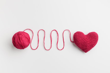 Crocheted amigurumi pink red heart with a cotton waved thread on a white background. Valentine's day banner with a copyspaceの写真素材