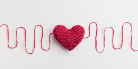 Crocheted amigurumi pink red heart with a cotton waved thread on a white background. Valentine's day banner with a copyspaceの写真素材