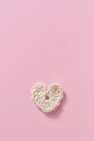 Crocheted amigurumi white heart on a pink background. Valentine's day banner with a copyspace