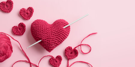 Crocheted amigurumi purple red burgundy hearts with crochet hook on a pink background. Valentine's...