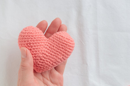 Crocheted amigurumi pink heart in a woman's hand. Valentine's day banner with a copyspaceの写真素材
