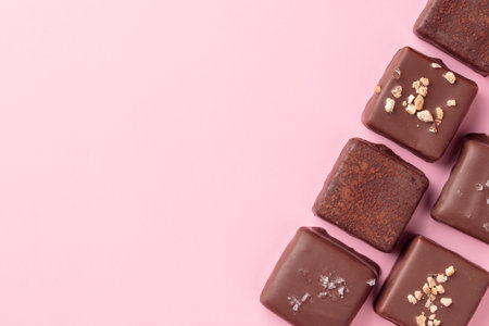 Assortment of handcrafted chocolate bonbons. Delicious dessert banner on a pink background with copyspaceの写真素材